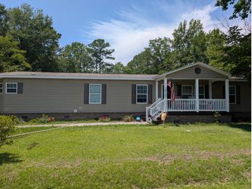 Charming one-story home featuring a cozy front porch, green lawn, and beautiful landscaping at 215 Hines Dr, Bonneau, SC 29431