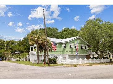 Charming two-story home with light green exterior, white picket fence, and a beautifully landscaped front yard at 2218 Myrtle Ave, Sullivans Island, SC 29482