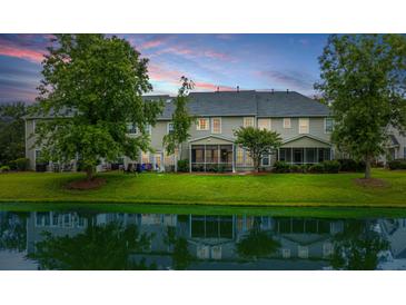 A serene backyard view featuring a lush lawn and pond, screened in porches, perfect for relaxation and outdoor living at 3012 Candela Grove Dr, Charleston, SC 29414