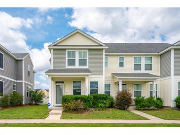Charming two-story townhome showcasing neat landscaping and inviting curb appeal on a sunny day at 3927 Four Poles Park Dr, North Charleston, SC 29405