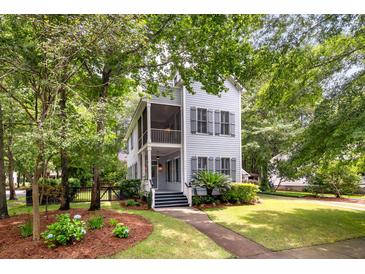 Charming two-story home features a welcoming porch, a meticulously landscaped yard, and mature trees enhancing its curb appeal at 5152 Coral Reef Dr, Johns Island, SC 29455