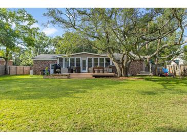 Expansive backyard features a well-maintained lawn, a deck and mature shade trees at 689 Port Cir, Charleston, SC 29412