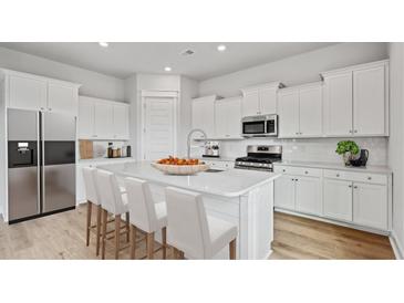 Modern kitchen featuring white cabinets, stainless steel appliances, and a quartz countertop island with bar seating at 89 French Garden Cir, Summerville, SC 29486