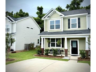 Charming home boasts a well-manicured lawn, complemented by lovely landscaping and a cozy front porch seating area at 9101 Parlor Dr, Ladson, SC 29456