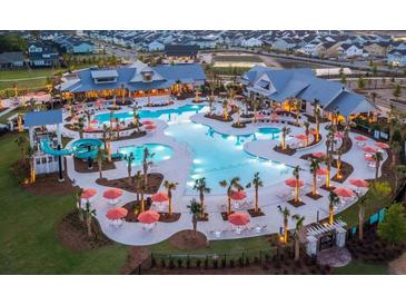 Stunning aerial view of a resort-style community pool, with palm trees, lounge chairs, umbrellas and a clubhouse in the background at 99 French Garden Cir, Summerville, SC 29486