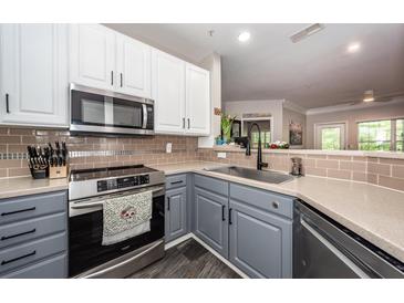 Well-lit kitchen featuring stainless steel appliances, modern tile backsplash, and gray and white cabinets at 1121 Basildon Rd, Mount Pleasant, SC 29466