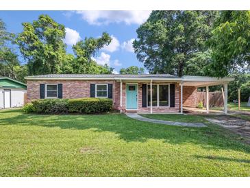 Charming brick home featuring a well-maintained lawn and a welcoming turquoise front door at 1520 Kirklees Abbey Dr, Charleston, SC 29407