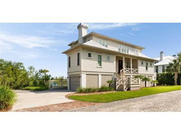 Charming two-story beach home featuring a covered porch, and a well-manicured lawn at 2618 Raven Dr, Sullivans Island, SC 29482