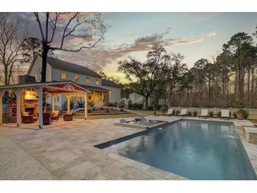 Stunning backyard featuring a pool, sun loungers, outdoor kitchen, and covered patio for ultimate relaxation at 1098 Reserve Ln, Awendaw, SC 29429