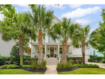 Charming two-story home with a welcoming front porch and beautifully landscaped yard with lush palm trees at 1407 Wando View St, Daniel Island, SC 29492