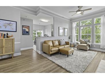 Bright living room featuring a leather sofa, ceiling fan, and large windows with natural light at 1735 Telfair Way, Charleston, SC 29412