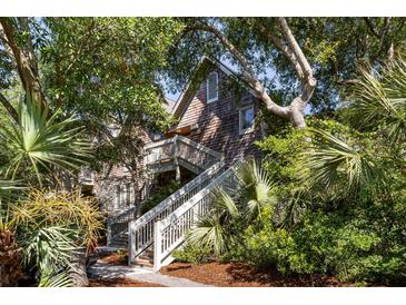 Charming cedar shake home exterior with inviting staircases, lush landscaping, and a rustic appeal at 3577 Shipwatch Rd, Kiawah Island, SC 29455