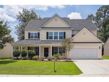 Inviting two-story home with a charming front porch, attached garage and lush landscaping at 7511 Hawks Cir, Hanahan, SC 29410