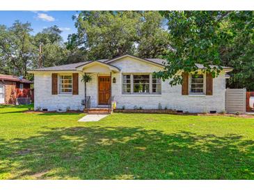Charming white brick home featuring manicured lawn, wood shutters, and inviting front porch at 111 Circle Dr, Summerville, SC 29485