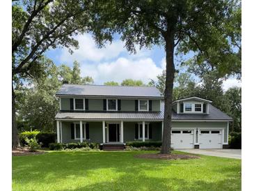 Charming two-story home with a well-maintained lawn, black shutters, and a detached two-car garage at 1211 Dennis Blvd, Moncks Corner, SC 29461