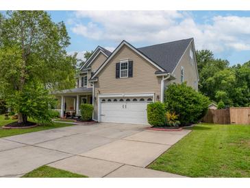 Inviting two-story home featuring a manicured lawn, attached two-car garage, and lush landscaping at 125 Spring Meadows Dr, Summerville, SC 29485