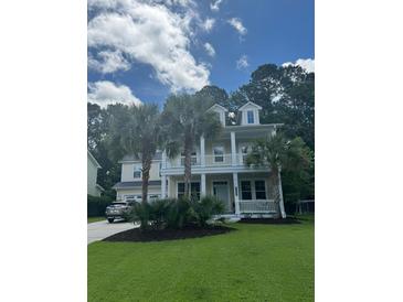 Charming two-story home with a well-manicured lawn, complemented by mature palm trees and a welcoming front porch at 1721 Wellstead St, Mount Pleasant, SC 29466