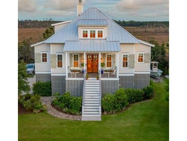Charming elevated home with a metal roof, manicured lawn, and inviting front porch at 1809 Rushland Grove Ln, Johns Island, SC 29455