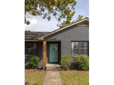 Charming gray brick home with a welcoming turquoise front door and mature trees at 5065 Durant Ave, North Charleston, SC 29405