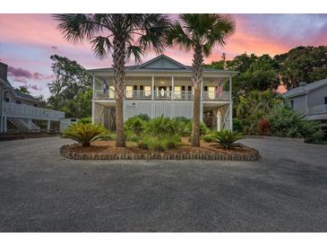Charming two-story beach house with double palm trees, covered porch, and a spacious driveway at 1604 Jungle Rd, Edisto Island, SC 29438