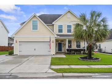 Charming two-story home featuring a well-manicured lawn, two-car garage, and a classic blue front door at 411 Topcrest Ln, Moncks Corner, SC 29461