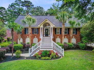 Beautiful brick home features a grand entrance with dual staircases and well-manicured landscaping at 4272 Persimmon Woods Dr, Charleston, SC 29420