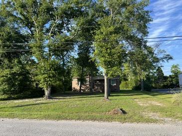 Charming single-story brick home nestled among mature trees with a lush green lawn at 9612 Hoot Owl Ave, Ladson, SC 29456