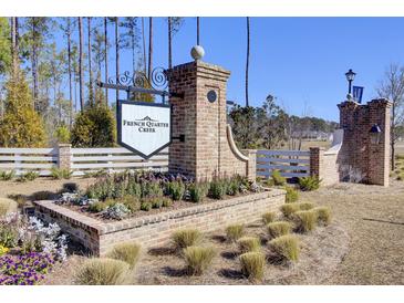 French Quarter Creek community entrance with brick pillars, sign, and well-maintained landscaping at 104 Wild Orchid Way, Huger, SC 29450