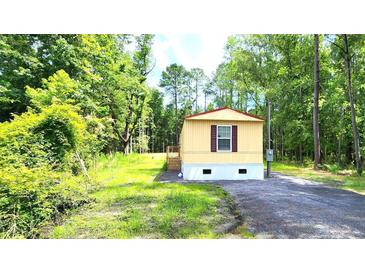 Cozy single-story home featuring light siding, a simple porch, and a shingled roof, nestled in a verdant, wooded setting at 149 Old Red Hill Rd, Ridgeville, SC 29472