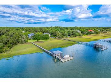 Stunning aerial view of waterfront homes, private docks, and lush green surroundings under a partly cloudy sky at 2287 Shoreline Dr, Johns Island, SC 29455