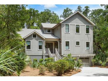 Charming two-story home with a landscaped yard and staircase leading to the front door at 3125 Privateer Creek Rd, Seabrook Island, SC 29455