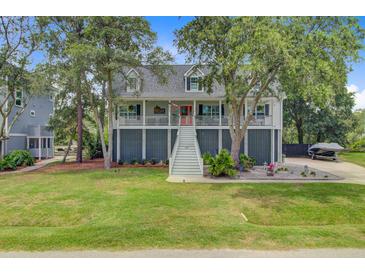 Charming raised home featuring lush landscaping, a large yard, and a welcoming front porch at 634 Lynne Ave, Charleston, SC 29412