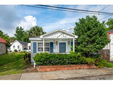Charming cottage-style home featuring blue shutters, a landscaped yard, and a cozy front porch at 9 F St, Charleston, SC 29403