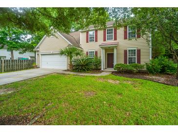 Charming two-story home with beige siding, red shutters, a well-manicured lawn, and an attached two-car garage at 1629 Jorrington Street St, Mount Pleasant, SC 29466