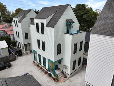 An exterior view of a three-story home with a gravel driveway and bright turquoise accents at 3 1/2 Maranda Holmes St # B, Charleston, SC 29403