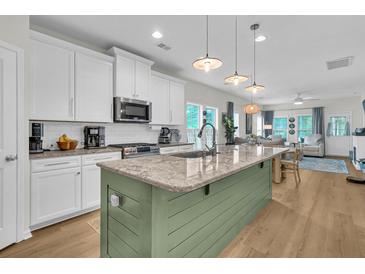 Bright open kitchen featuring granite countertops, stainless steel appliances, and an island overlooking the living area at 3789 Tupelo Branch Row, Mount Pleasant, SC 29429