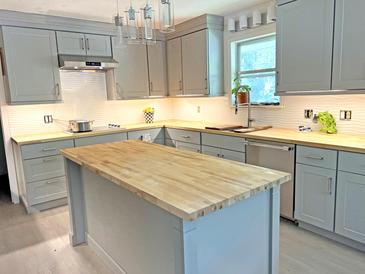 Modern kitchen featuring gray cabinets, butcher block countertops, an island, and stainless steel appliances at 1014 E Cooper Ave, Folly Beach, SC 29439