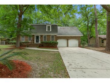 Charming brick home features a two-car garage and mature trees surrounding the property at 105 Spring St, Summerville, SC 29485