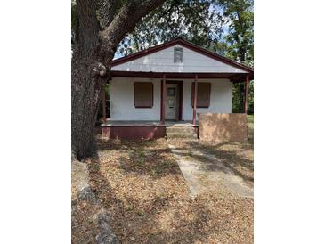 Modest, single-story home with a small porch, red trim, and boarded-up windows on a tree-filled lot at 204 Lewis St, Walterboro, SC 29488