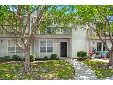 Charming two-story condo with white siding, a walkway, mature trees, and a private second-story balcony at 7814 Nummie Ct, North Charleston, SC 29418