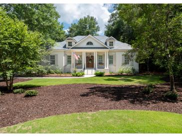 Charming white brick home featuring a landscaped front yard, columns, and a welcoming front porch at 441 Elfes Field Ln, Charleston, SC 29492