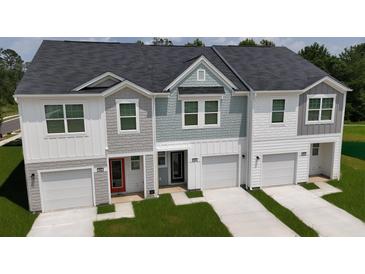 New townhomes featuring varied siding, dark roofing, attached garages, and manicured lawns at 495 Colchester Ct, Moncks Corner, SC 29461