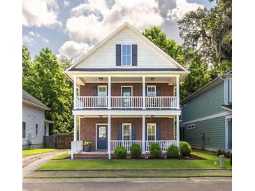 Charming two-story home features a brick facade and double balconies with lush landscaping at 5110 Hyde Park Village Ln, North Charleston, SC 29405