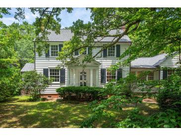 Charming white two-story home with black shutters surrounded by lush green foliage at 6 Sayle Rd, Charleston, SC 29407