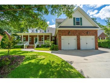 Charming brick home with a manicured lawn and a two-car garage on a sunny day at 8725 Herons Walk, North Charleston, SC 29420