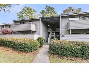 Exterior view of a well-maintained condo building with landscaped bushes and gray facade at 902 Greenmeadow Dr, Goose Creek, SC 29445