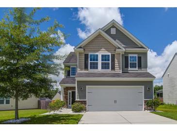 Charming two-story home featuring a well-maintained lawn and attached two-car garage at 9680 Spencer Woods Rd, Ladson, SC 29456