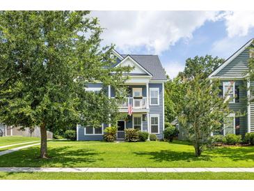 Charming two-story home featuring a double balcony, tidy lawn, and mature shade trees at 1070 Moss Grove Dr, Moncks Corner, SC 29461