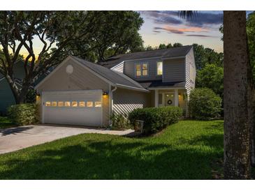 Charming two-story home featuring an attached garage, beautiful landscaping, and a welcoming front entrance with a wreath at 1406 Oaklanding Rd, Mount Pleasant, SC 29464