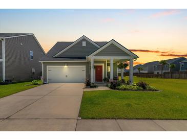 Charming single-Gathering home features a well-manicured lawn, covered porch, and an attached two-car garage at sunset at 160 Greenbelt Ct, Summerville, SC 29485